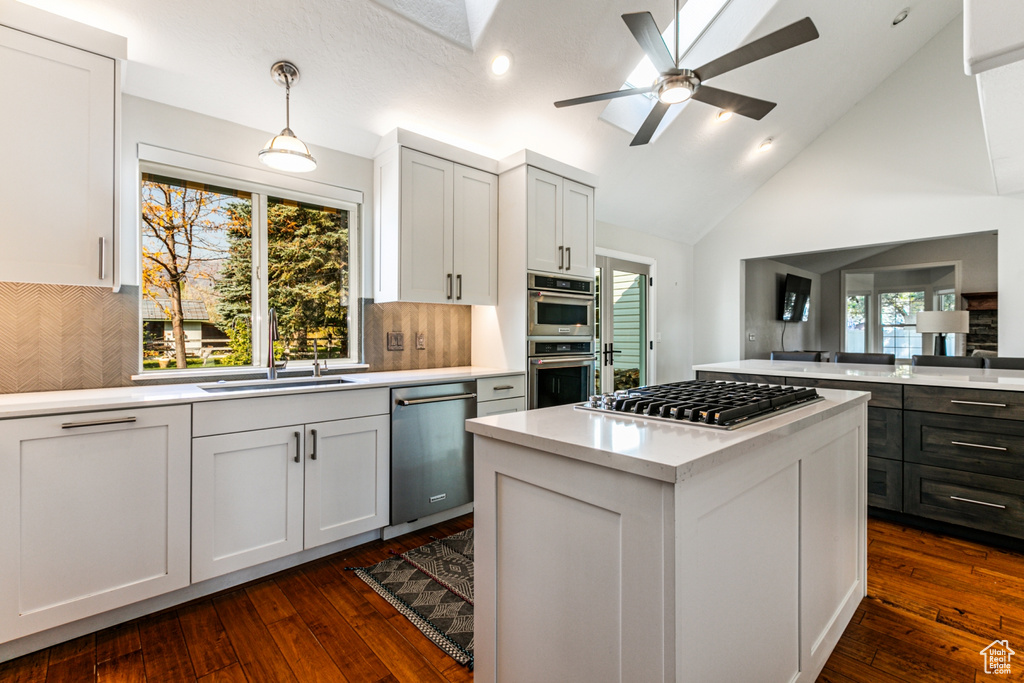 Kitchen with appliances with stainless steel finishes, white cabinetry, dark wood-type flooring, and plenty of natural light