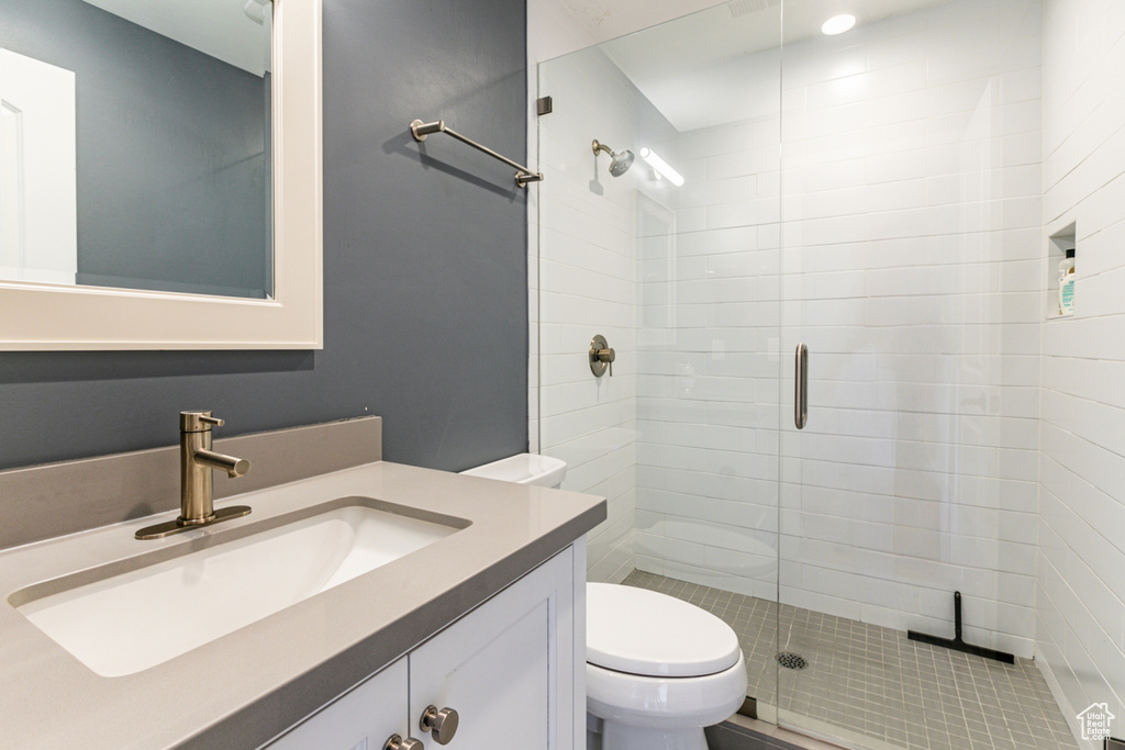 Bathroom featuring vanity, toilet, and a shower with shower door