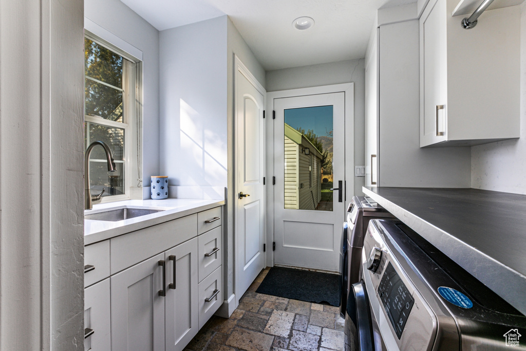 Washroom featuring sink, washer and clothes dryer, and cabinets