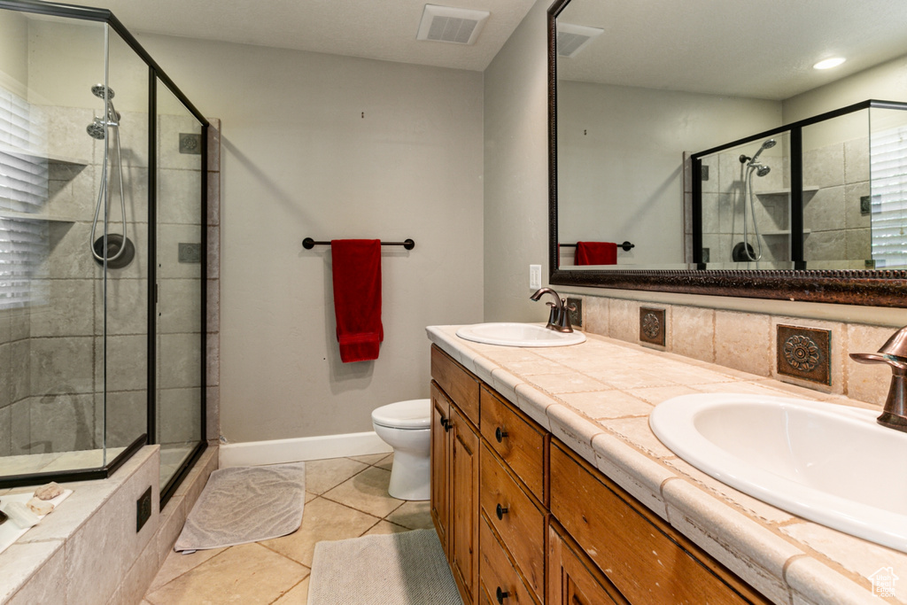 Bathroom with a shower with door, vanity, toilet, and tile patterned flooring