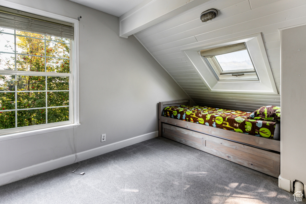 Unfurnished bedroom featuring lofted ceiling with skylight and carpet