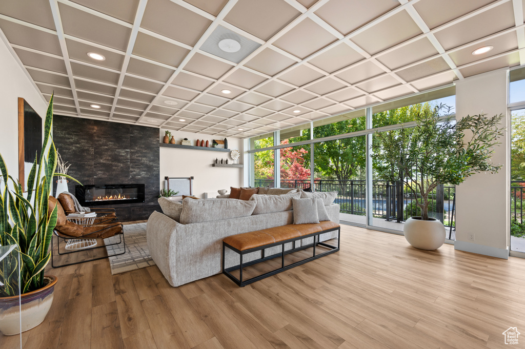 Living room featuring hardwood / wood-style floors, a tiled fireplace, coffered ceiling, and expansive windows