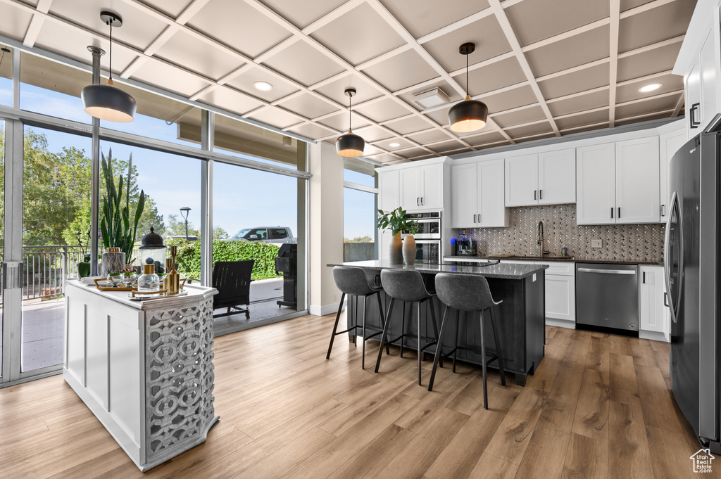 Kitchen featuring white cabinets, stainless steel appliances, decorative light fixtures, and a kitchen island