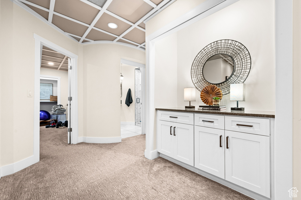 Corridor featuring coffered ceiling and light colored carpet