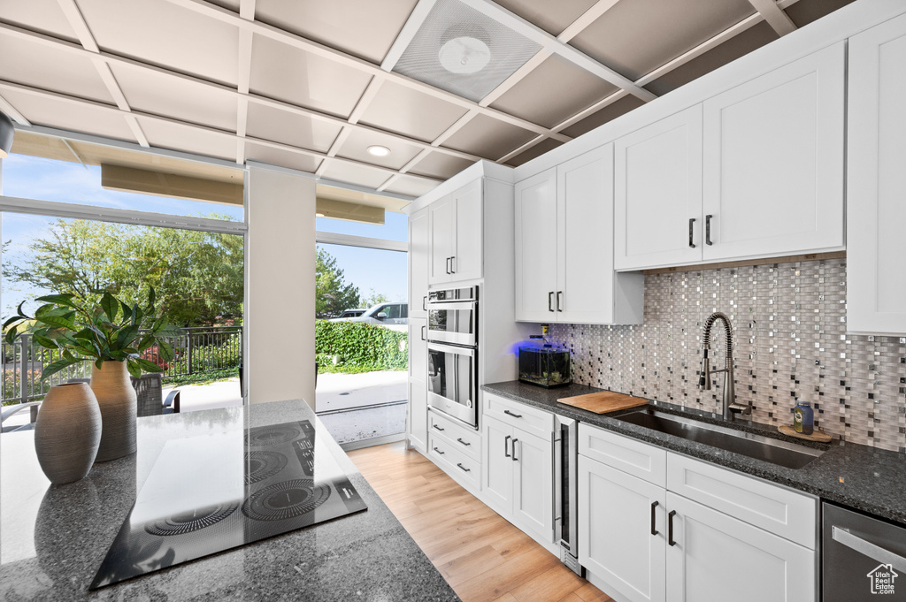 Kitchen with white cabinetry, stainless steel appliances, and dark stone counters