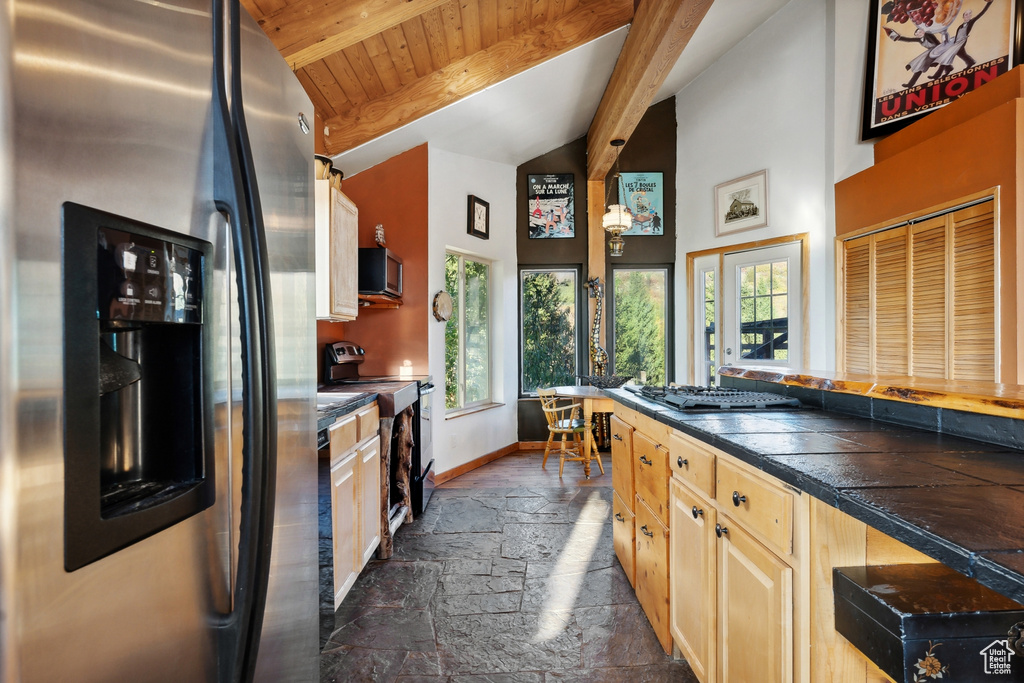 Kitchen featuring stainless steel appliances, a wealth of natural light, light brown cabinets, and lofted ceiling with beams