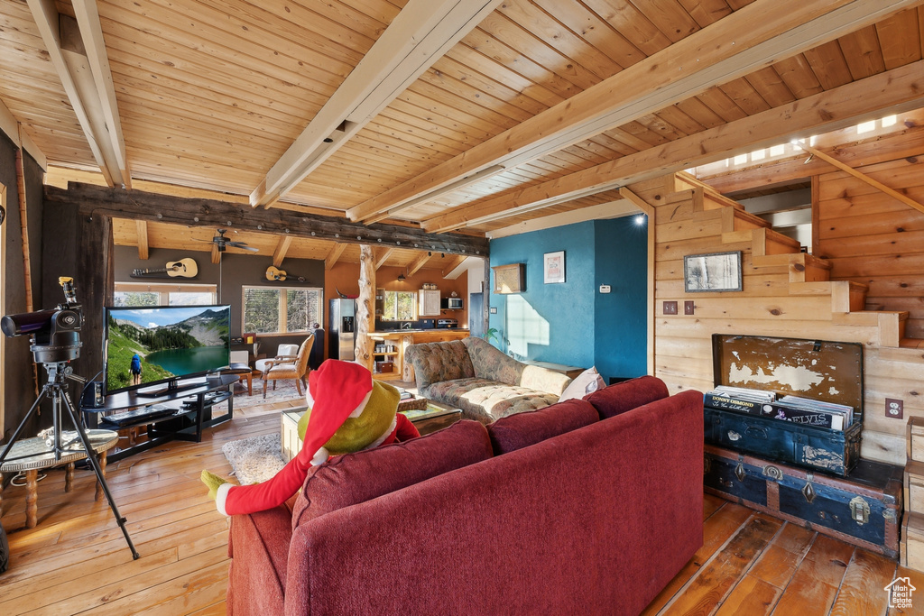 Living room with wooden walls, wood-type flooring, beamed ceiling, and wooden ceiling