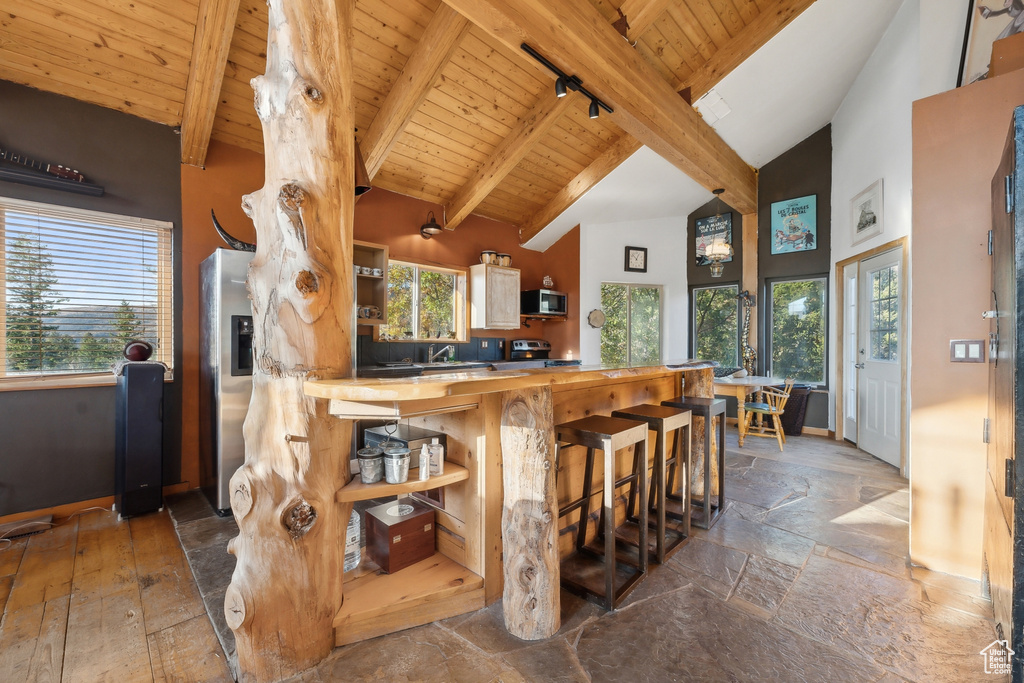 Kitchen featuring plenty of natural light, butcher block counters, appliances with stainless steel finishes, and a kitchen bar