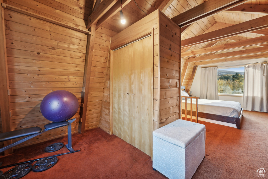 Exercise room featuring wood ceiling, vaulted ceiling, wooden walls, and dark carpet