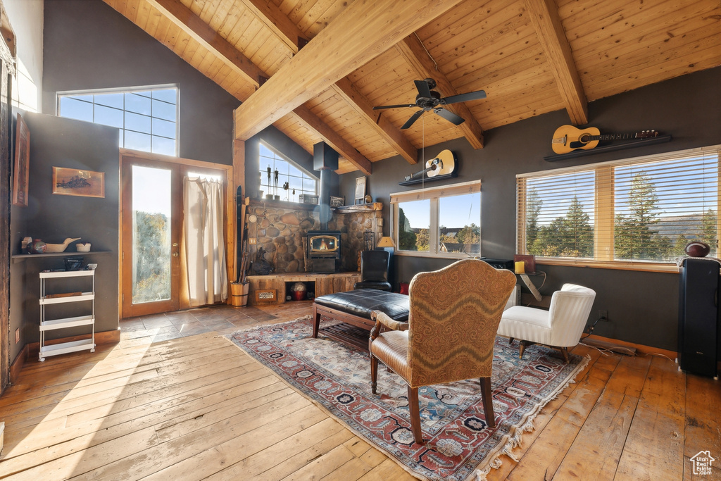 Living room featuring wood ceiling, beam ceiling, a wood stove, light wood-type flooring, and high vaulted ceiling