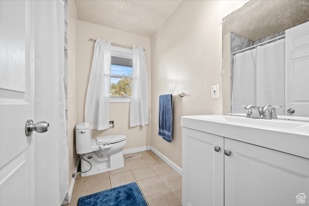 Bathroom featuring vanity, toilet, and tile patterned flooring