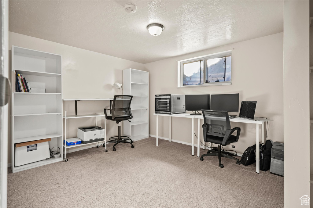 Carpeted home office featuring a textured ceiling