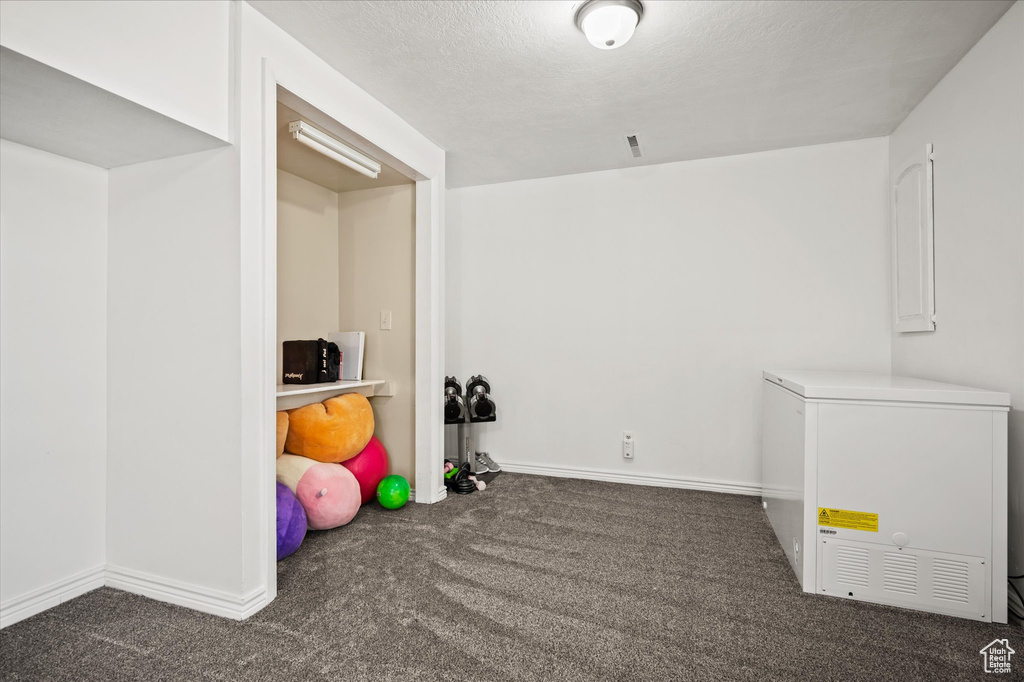 Playroom featuring a textured ceiling and dark colored carpet