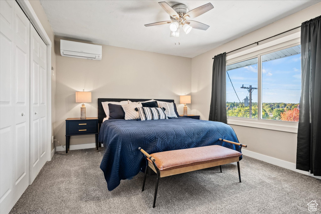 Bedroom featuring a closet, carpet floors, a wall mounted AC, and ceiling fan