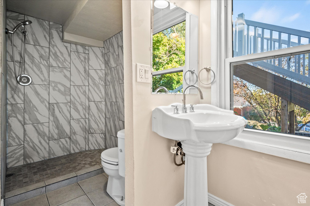 Bathroom featuring toilet, a tile shower, and tile patterned floors