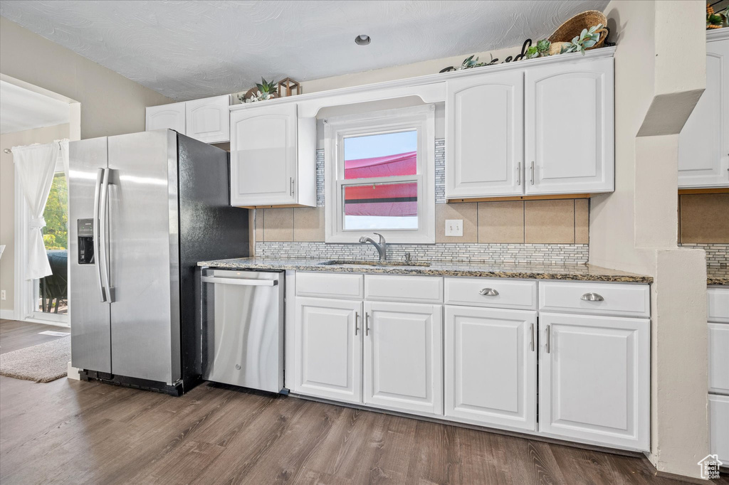 Kitchen featuring appliances with stainless steel finishes, white cabinets, sink, and a wealth of natural light