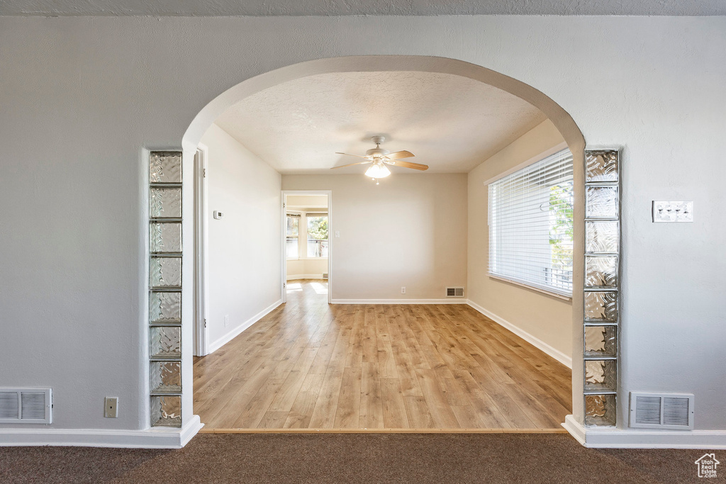 Unfurnished room featuring ceiling fan, a textured ceiling, and light hardwood / wood-style flooring