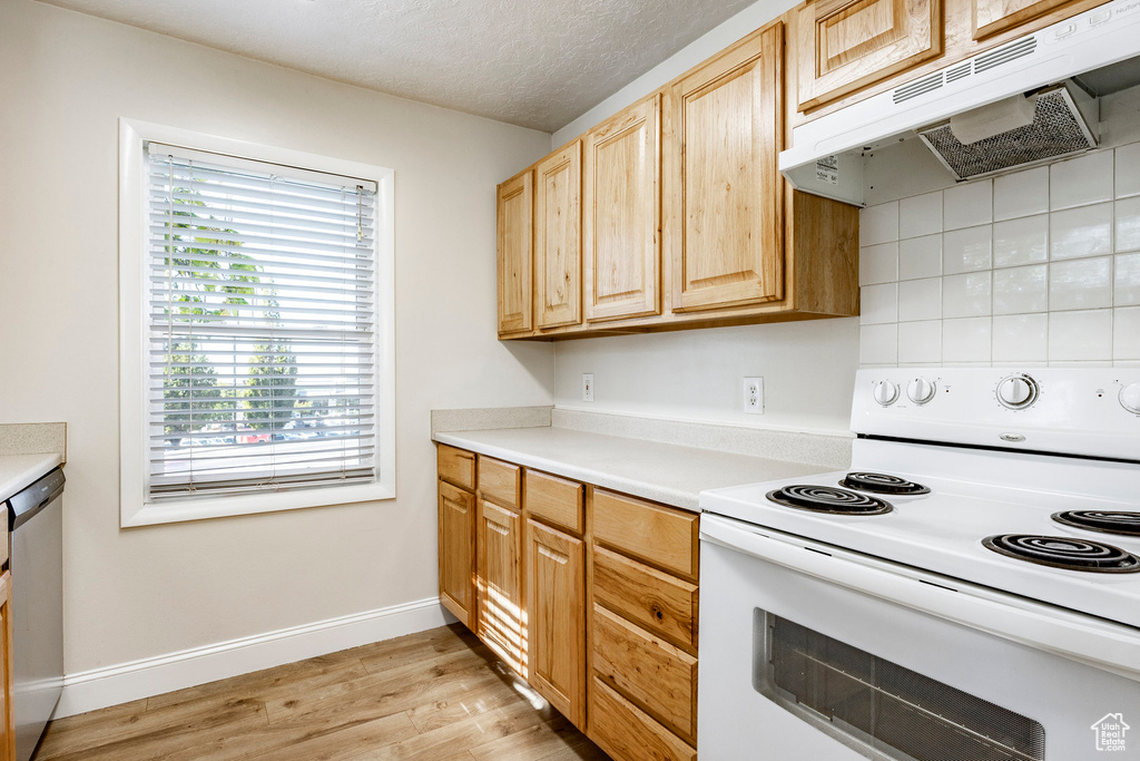 Kitchen featuring light brown cabinets, a textured ceiling, white range with electric cooktop, light hardwood / wood-style flooring, and dishwasher