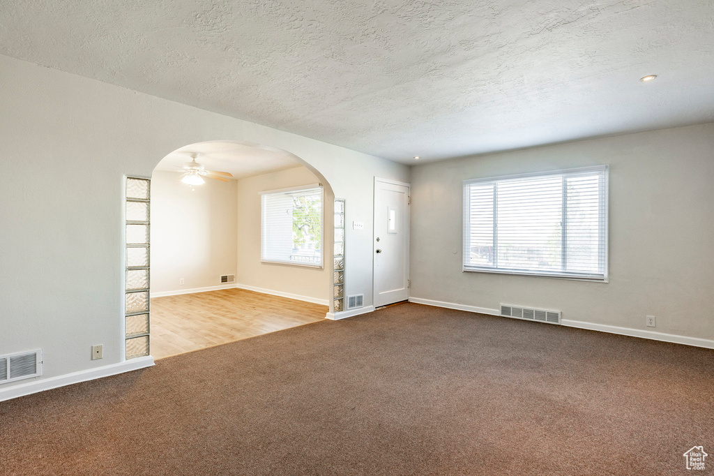 Unfurnished room featuring a textured ceiling, hardwood / wood-style flooring, and ceiling fan