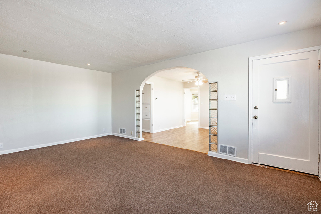 Empty room featuring ceiling fan, a textured ceiling, and light hardwood / wood-style floors