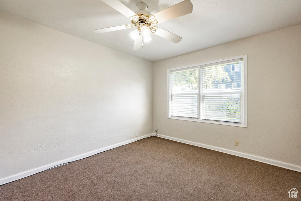 Carpeted empty room featuring ceiling fan