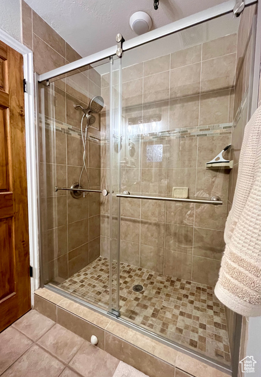 Bathroom with a textured ceiling, walk in shower, and tile patterned floors