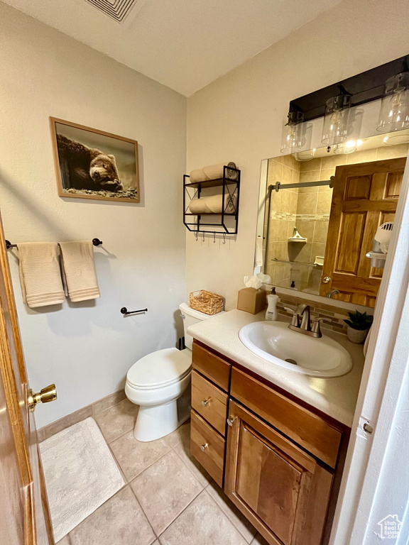 Bathroom with vanity, tile patterned flooring, toilet, and tiled shower