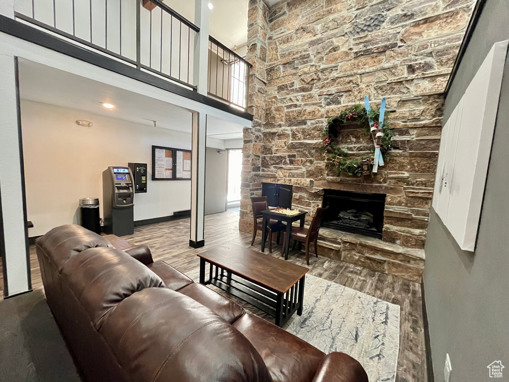 Living room with wood-type flooring, a high ceiling, and a fireplace