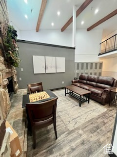 Living room featuring beamed ceiling, hardwood / wood-style floors, and a stone fireplace