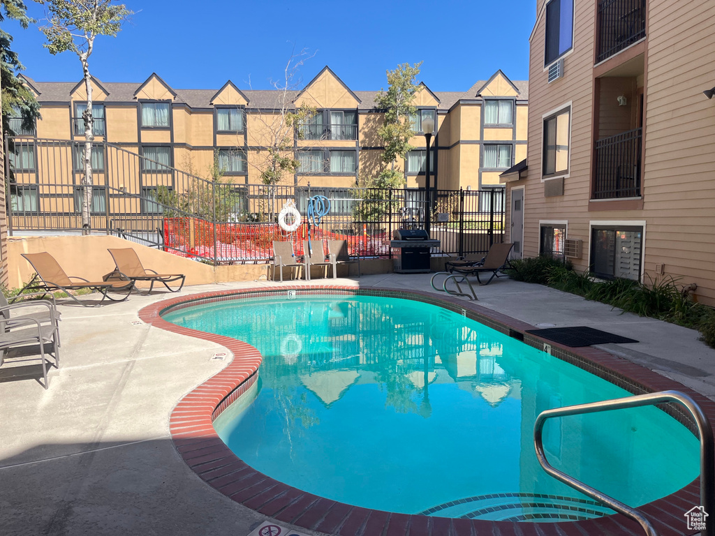 View of pool with a patio and a grill