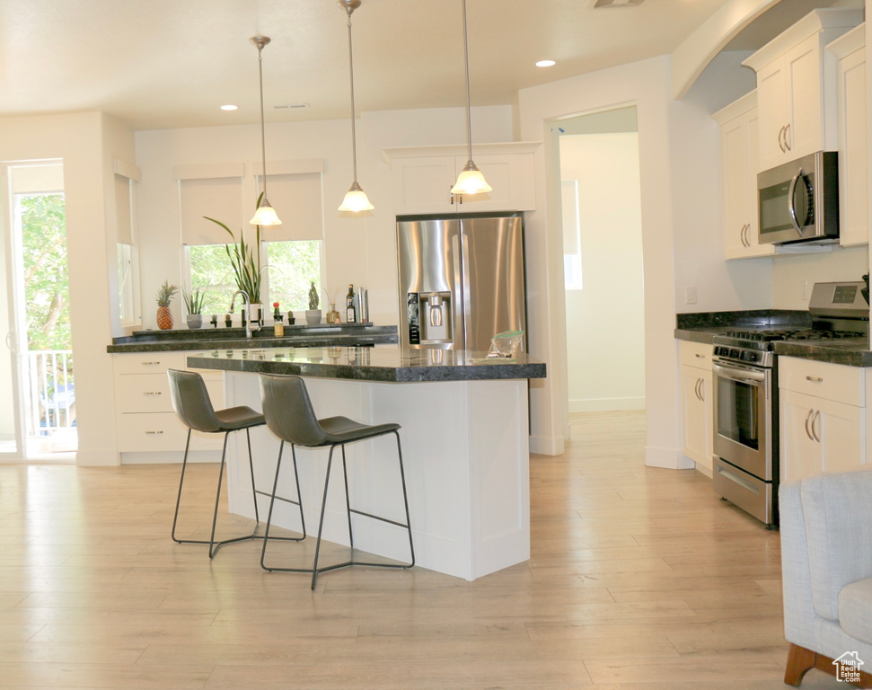 Kitchen featuring white cabinetry, appliances with stainless steel finishes, plenty of natural light, and a kitchen island