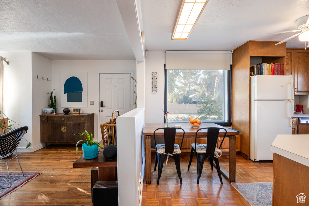 Dining room with a textured ceiling, light parquet floors, and ceiling fan