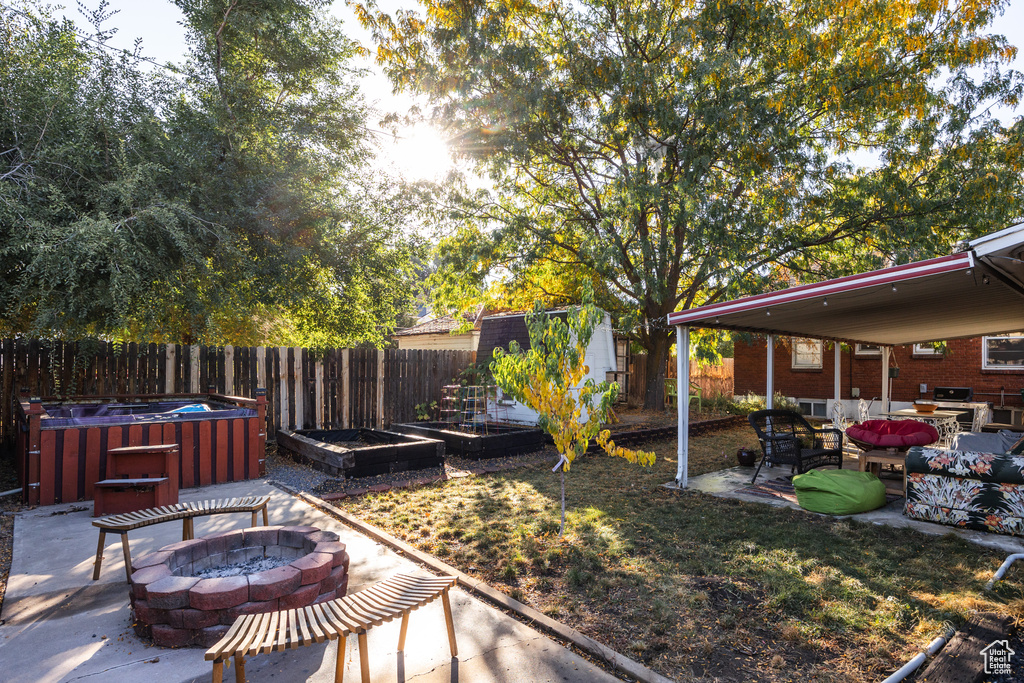 View of yard with a patio area, a hot tub, a fire pit, and a storage shed