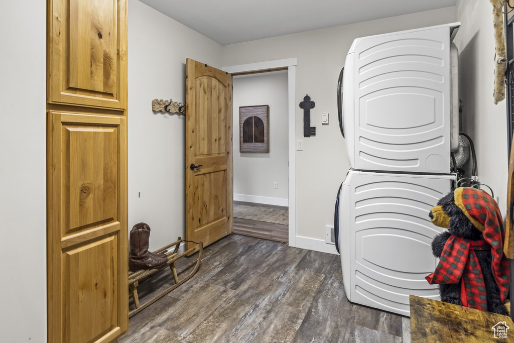 Washroom featuring dark hardwood / wood-style floors and stacked washing maching and dryer