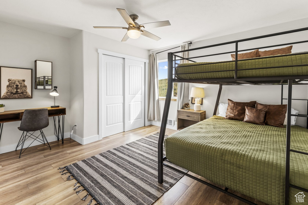 Bedroom featuring light hardwood / wood-style floors, a closet, built in desk, and ceiling fan