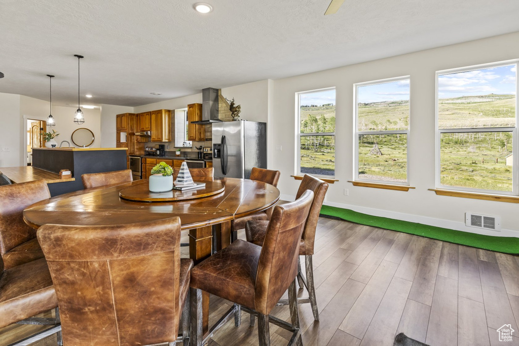 Dining space featuring hardwood / wood-style flooring, golf simulator, and a wealth of natural light