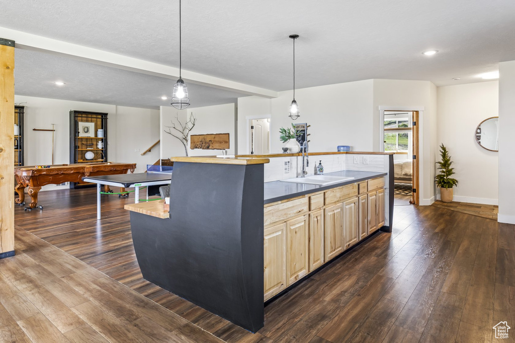 Kitchen with sink, a kitchen island with sink, hanging light fixtures, and dark hardwood / wood-style flooring