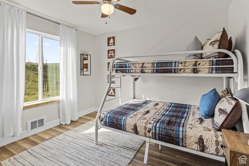 Bedroom featuring multiple windows, wood-type flooring, and ceiling fan