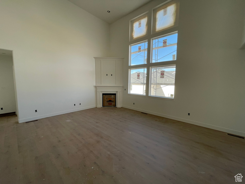 Unfurnished living room with a towering ceiling and light wood-type flooring