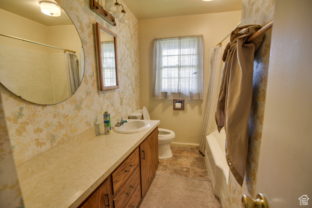 Full bathroom with toilet, vanity, and shower / tub combo