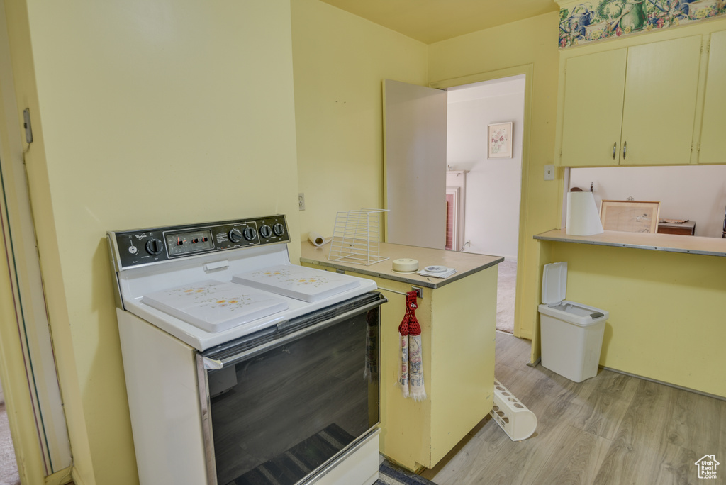 Kitchen featuring light wood-type flooring, electric range, and kitchen peninsula
