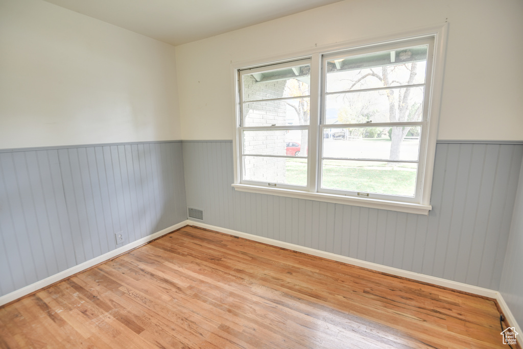 Empty room featuring a healthy amount of sunlight, wooden walls, and light wood-type flooring