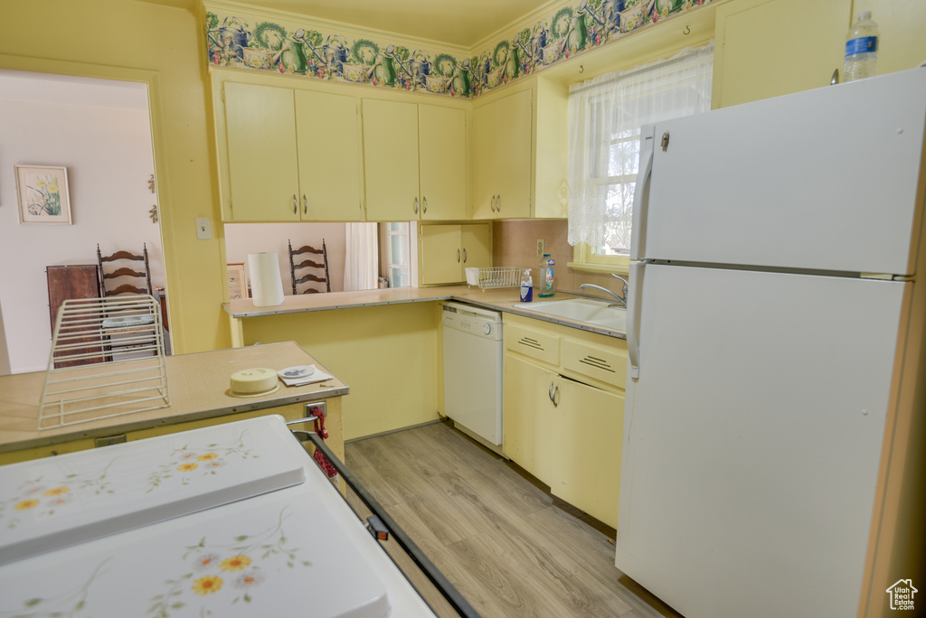 Kitchen featuring white appliances, sink, light wood-type flooring, cream cabinetry, and ornamental molding