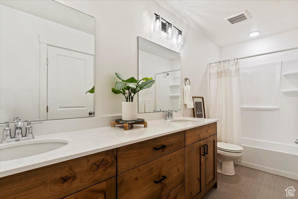 Full bathroom featuring vanity, toilet, and shower / bathtub combination with curtain