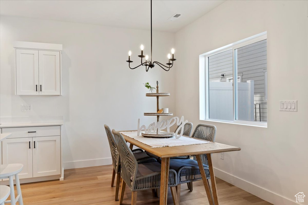 Dining room with light hardwood / wood-style flooring and a notable chandelier