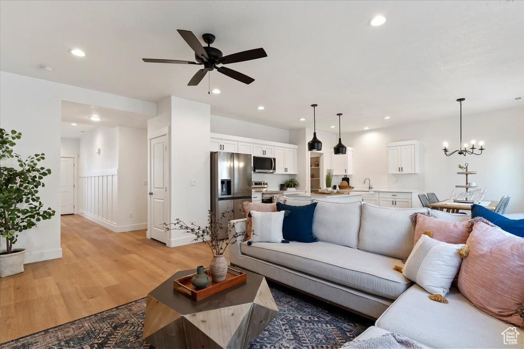 Living room featuring sink, ceiling fan with notable chandelier, and light wood-type flooring