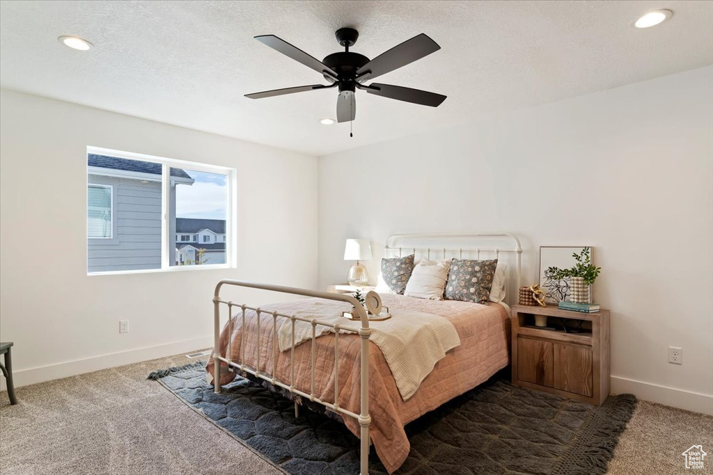 Carpeted bedroom featuring a textured ceiling and ceiling fan