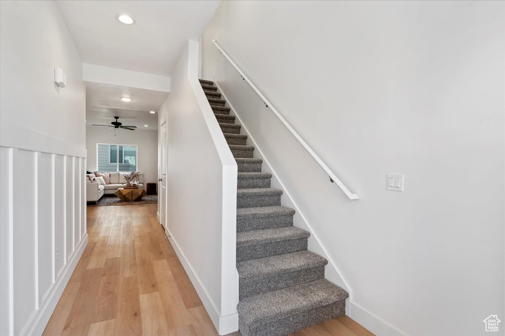 Stairs with hardwood / wood-style floors and ceiling fan