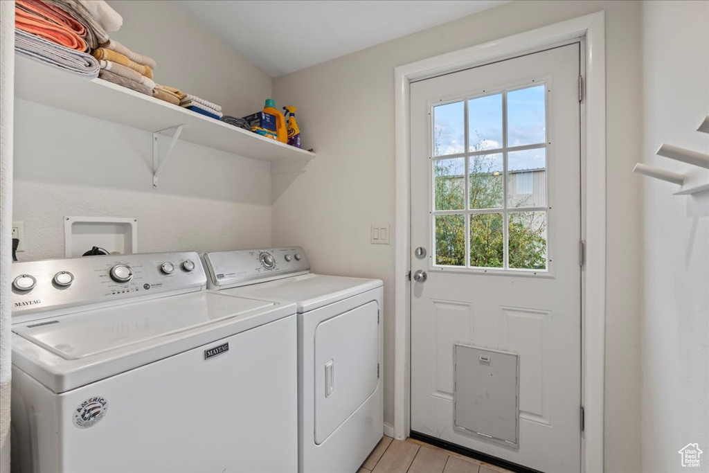 Clothes washing area featuring washer and clothes dryer and light wood-type flooring