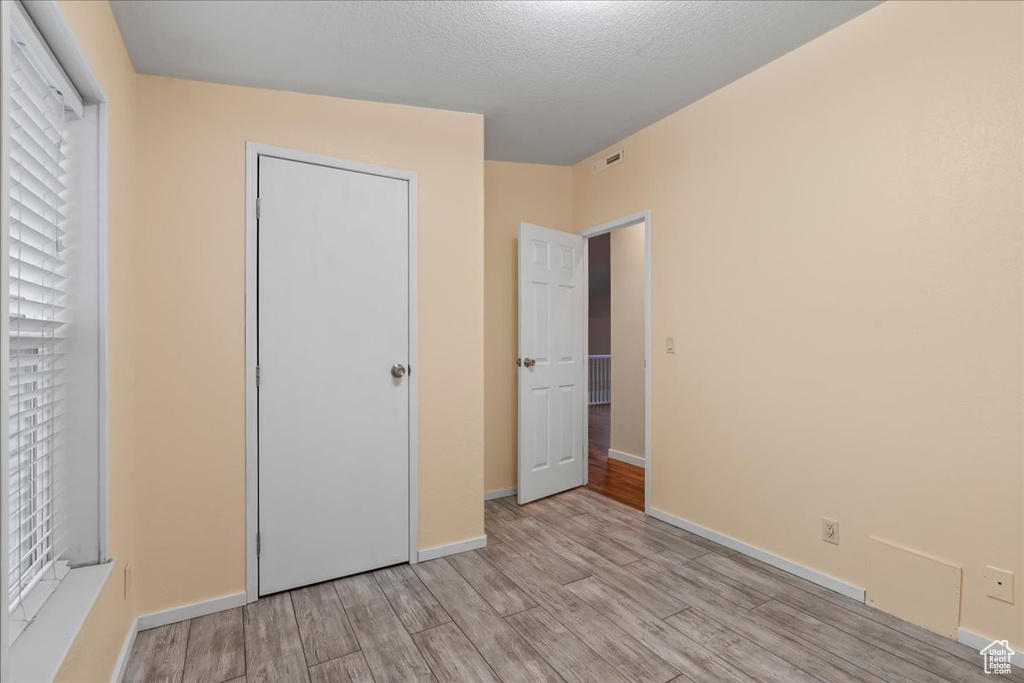 Unfurnished bedroom featuring a textured ceiling and light hardwood / wood-style flooring